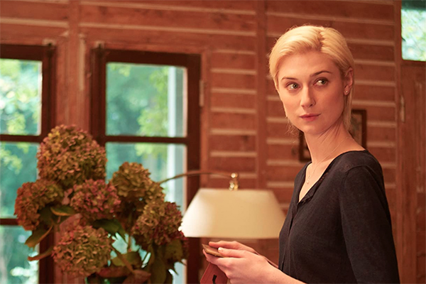 White woman with blonde hair holding a picture frame while looking back over her shoulder